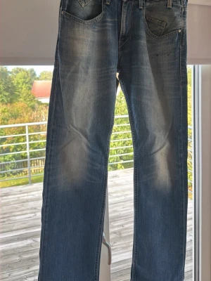 Levi's jenas 504 - Säljer ett par klassiska blå jeans från Levi's med rak passform och snyggt slitna detaljer framtill och baktill. Jeansen har fem fickor, normal midja och är tillverkade i slitstark denim. Perfekta för en avslappnad och trendig look.