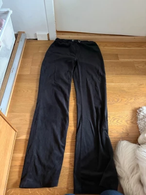 Svarta mjukisbyxor från Gina Tricot - Ett par svarta mjukisbyxor från Gina Tricot i storlek XXS. Byxorna har raka ben och resår i midjan med dragsko. Tillverkade i mjukt och bekvämt material som passar perfekt för chill dagar hemma eller när du vill ha en avslappnad stil.