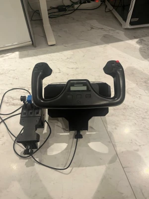 Flygsimulator ratt och throttle - Säljer en svart flygsimulator handkontroll med ratt och separat throttle-enhet. Ratten har flera knappar och en display, medan throttle-enheten har reglage i blått, rött och svart. Perfekt för dig som vill ta din flygsim-upplevelse till nästa nivå.