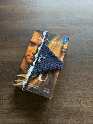 Blått virkat bokmärke  - Ett bokmärke i form av en trosa med spetskant och en liten rosett framtill 
