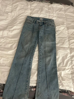Ljusblå bootcut jeans med streck - Säljer ett par ljusblå bootcut/flare jeans med coola veck framtill. Har små missfärgningar längst ner som nästan inte syns, men därav hör bara av er för fler bilder💞