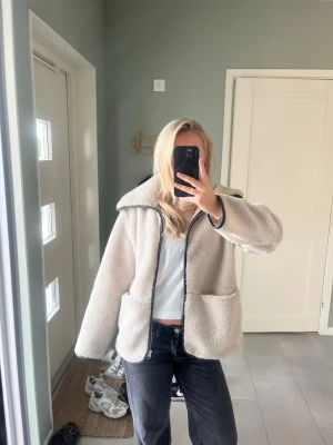 teddyjacka arket  - Nypris 1600. Mysig beige teddyjacka med stor krage och svarta detaljer längs dragkedjan och ärmsluten. 
