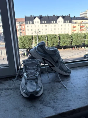 Vita och silverfärgade sneakers - Snygga sneakers i vitt och silver med meshdetaljer och reflexliknande partier. Skorna har en sportig look med snörning och en bekväm, vadderad sula. Perfekta för dig som gillar en clean och modern stil.