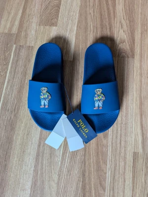 Polo Ralph Lauren tofflor - Tjena! Jag säljer ett par Riktigt snygga Ralph Lauren tofflor😁  De är helt nya och är aldrig använda (de har tagsen kvar) Dem är självklart äkta✅ Skicka om du har några frågor☺️