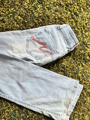 Ljusblå nelly bootcut jeans med broderad ficka💕 - Säljer ett par ljusblå lowwaist bootcut jeans från Nelly med snygg rosa broderad detalj på bakfickan.  Älskar byxorna och hur dom sitter men tyvvär inte min stil längre🥺De är lite slitna längst ner kolla sista bilden. Dem är också slutsålda på Nelly!