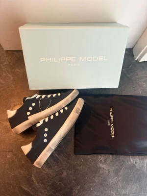 Philippe Model mörkblåa sneakers - Snygga mörkblåa sneakers från Philippe Model med vita detaljer och snörning. Klassisk låg modell med vit sula och vita skosnören. Perfekta för dig som vill ha en stilren och trendig look. Kommer med originalkartong och dustbag.( vet dock ej om dom är äkta eller kopior) 