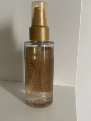Wella Luxe Oil hårolja 100 ml - Wella Luxe Oil är en närande hårolja i en genomskinlig plastflaska med guldfärgad pump. Innehåller 100 ml och ger håret glans och mjukhet. Perfekt för att skydda och vårda håret med en lyxig känsla.