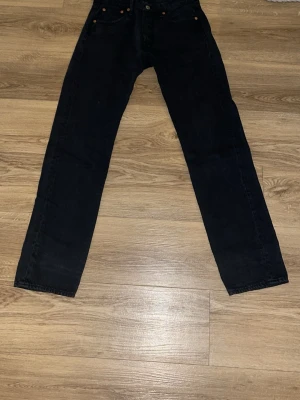 Svarta raka jeans - Säljer ett par svarta jeans med rak passform och klassisk femficksdesign. Jeansen har knappgylf och detaljer i kopparfärg. Materialet är denim i bomull och de har en tidlös look som passar till det mesta.