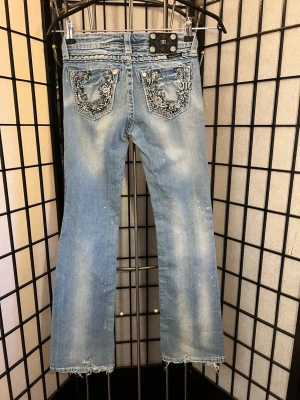 🔥 Miss Me Y2K Bootcut Jeans Girls 12 💎 - DRÖMJEANS för dig som älskar Y2K & McBling 💎🔥 Äkta Miss Me bootcut i supersnygg ljusblå tvätt, låg midja och ikoniska bakfickor med broderier, strass och nitar ✨🤠 Perfekta till sneakers eller boots!  Märkta Girls 12 – kan passa ca 12–17 år beroende på kroppsform. Kolla måtten 👇  💙 Midja: 30 cm plant 💙 Innerben: 74 cm 💙 Totallängd: 95 cm 💙 Midjehöjd: 18–20 cm  Välanvänd/distressed look med slitna benslut, små hål/fläckar och ev. saknad dekor. Se bilder 🫶  📦 Skickas snabbt!
