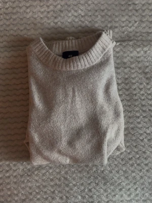 Beige stickad tröja från H&M - Mysig beige stickad tröja från H&M i regular fit. Tröjan har rund halsringning och ribbade muddar vid halsen. Perfekt för lager på lager och enkel att matcha med olika outfits.