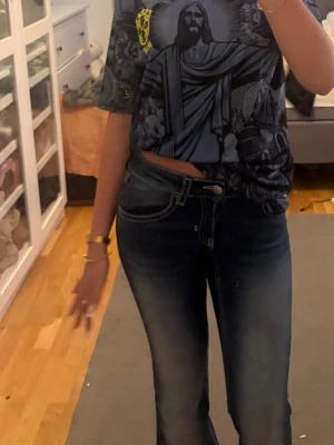 Mörkblå bootcut jeans med broderi - Säljer ett par mörkblå bootcut jeans med snygga slitningar och broderade bakfickor med knappar. Jeansen har kontrastsömmar och klassisk femficksmodell. Perfekta för dig som gillar en avslappnad men ändå trendig stil.