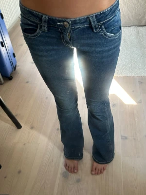 Mörkblå bootcut jeans med kontrastsömmar från Gina tricot  - Snygga mörkblå bootcut jeans med vita kontrastsömmar . Jeansen har låg midja och utsvängda ben, vilket ger en retrovibe. Materialet är denim med stretch för extra komfort. Perfekta för dig som gillar en avslappnad men trendig stil.