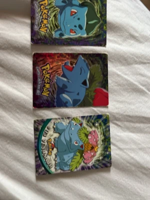 Pokémon samlarkort Bulbasaur Ivysaur Venusaur - Tre Pokémon samlarkort med Bulbasaur, Ivysaur och Venusaur. Korten har färgstarka illustrationer och holografisk effekt. Perfekt för dig som gillar att samla på Pokémon eller vill utöka din samling med klassiska karaktärer.