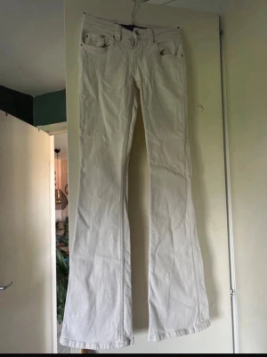 Vita bootcut jeans med broderad ficka - Säljer ett par vita bootcut jeans med snygg broderad detalj på bakfickan. Jeansen har klassisk femficksmodell och är tillverkade i ett mjukt bomullsmaterial med lite stretch. Perfekta för dig som gillar en avslappnad men trendig look.