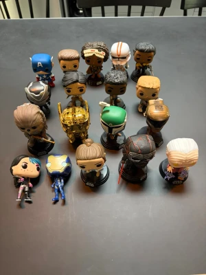 Samling Funko Pop-figurer Star Wars & Marvel - Säljer en samling Funko Pop-figurer med karaktärer från Star Wars och Marvel. Figurerna är färgglada och detaljerade, flera står på svarta baser med Star Wars-logga. Bland karaktärerna finns Chewbacca, C-3PO, Kylo Ren, Captain America och fler. Perfekt för samlare eller nördar!