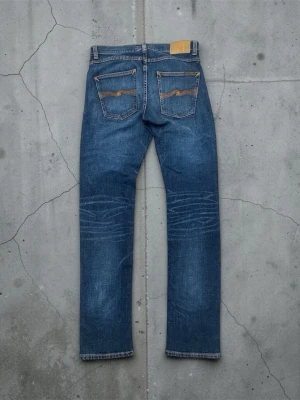 Nudie grim tim - Säljer ett par Nudie Jeans Grim Tim W31/L32  Riktigt snygga vintage Nudie Grim Tim med fina fades och en härlig använd känsla. Klassisk blå denim med mycket karaktär.  Slim straight passform, sitter snyggt och bekvämt.  Storlek: W31/L32 Fint skick
