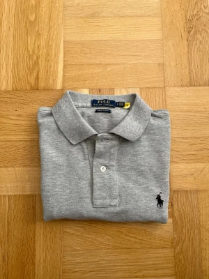 Ny & Äkta Ralph Lauren Piké - En stilren piké från märket Ralph lauren i färgen grå. Den är i storlek S samt modellen custom slim fit och är köpt från debut (påse finns kvar). Vid frågor eller funderingar är det bara att höra av sig! 😁