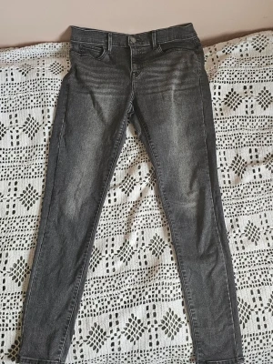 Gråa skinny jeans - Säljer ett par gråa skinny jeans med lätt slitna detaljer och klassisk femficksmodell. Jeansen har normal midja och smala ben, perfekta till en avslappnad stil. Materialet är stretchigt denim för extra komfort.