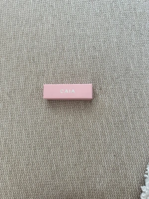 Juicy lip oil från CAIA - Lip oil från CAIA i en stilren, ljusrosa fyrkantig hylsa med vit text. Förpackningen är i hård plast och känns modern och trendig. Perfekt för dig som gillar smink med en clean look.Oöppnad och oanvänd, förpackningen är plomberad