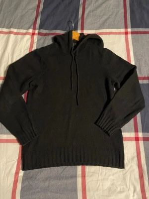 Svart stickad hoodie - Stilren svart stickad hoodie med huva från Dressmann i mycket fint skick. Ett mjukt och skönt plagg som passar perfekt till både jeans, chinos eller shorts under kyliga sommarkvällar.  