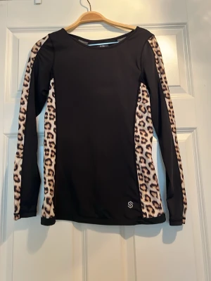 NY Träningströja från stronger med leopardmönster - Ny snygg träningströja i svart med leopardmönstrade längs ärmar och sidor. Mycket stretchigt och luftigt som andas, perfekt för all typ av träning 🐆