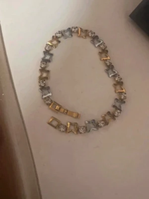 Guld- och silverfärgat armband - Snyggt armband i både guld- och silverfärg med växelvis fyrkantiga länkar och glittrande pärlor. Armbandet har en unik design där metall och pärlor varvas, vilket ger en cool och modern look. Perfekt accessoar för att lyfta din outfit.