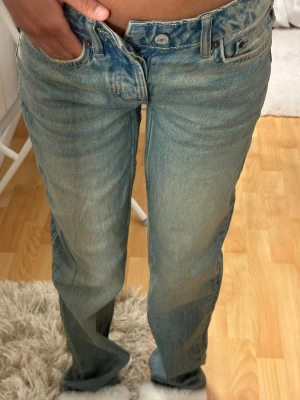 Ljusblå raka jeans med hög midja - Säljer ett par ljusblå jeans med rak passform och hög midja. Jeansen har klassiska fem fickor och knappgylf. Perfekta för en avslappnad och trendig look.