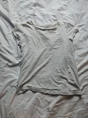 Ljusgrå basic t-shirt från H&M - En enkel och stilren ljusgrå t-shirt från H&M. T-shirten har rund halsringning och korta ärmar. Tillverkad i mjuk bomull som känns skön mot huden. Perfekt att matcha med jeans eller shorts för en avslappnad look.