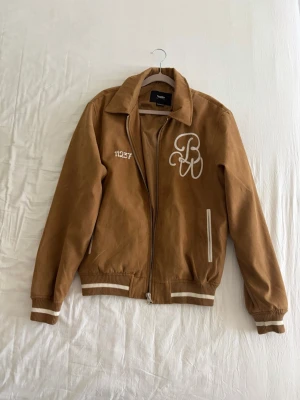 Suedejacka brun   - Snygg brun höstjacka med vita broderade detaljer. Från Pull & Bear, nästan nytt skick. Storlek S