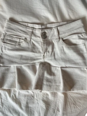 Vit jeanskjol med volang - Snygg ljus beige jeanskjol med volang nertill. Kjolens omsydd från ett par jeans.