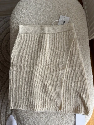 Beige ribbad kjol från NA-KD - Trendig beige ribbad kjol från NA-KD i kort modell. Kjolen har en mjuk stickad struktur och elastisk midja för skön passform. Perfekt att styla med en enkel topp eller oversized tröja för en avslappnad look.