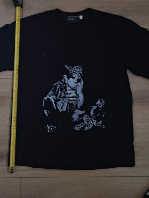 Svart t-shirt Enfants Riches Déprimés - Svart t-shirt från Enfants Riches Déprimés i storlek S. T-shirten har ett unikt vitt tryck framtill med konstnärligt motiv. Klassisk rund hals och korta ärmar. Perfekt för dig som gillar streetwear med edge.