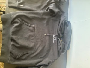 Svart hoodie från Polo Ralph Lauren - Säljer en svart hoodie från Polo Ralph Lauren med broderad logga på bröstet och liten vit häst på ärmen. Klassisk känguruficka framtill och justerbar dragsko i huvan. Tillverkad i mjukt bomullsmaterial för skön känsla.