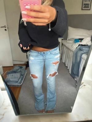 Ljusblå slitna bootcut jeans - Säljer ett par ljusblå bootcut jeans med stora slitningar och hål på låren och knäna. Passa inte mig så säljer därför vidare.