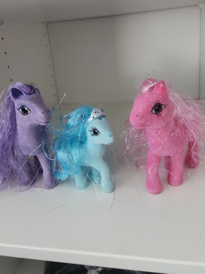 3 st.Häst figurer glitter - Tre häst figurer i glitterdesign, en blå med tiara och blå man, en lila med lila man och en rosa med rosa man. Alla har långa glittriga manar och stora ögon. Perfekta för samling eller lek.