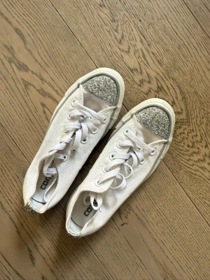 Converse sneakers - Ett par skitsnygga converse all star med glitterdetaljer. Säljer då de inte riktigt passade min form på foten. Annars inga slitningar och i bra skick!! Storlek 35 men skulle säga att de passar 36 också