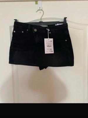 Jeans kjol - Svart jeans kjol från Pull&bear med inbyggda shorts. Knäppningen är asymmetrisk och har två knappar, se bild. Aldrig använd. Öppen för prisförslag.