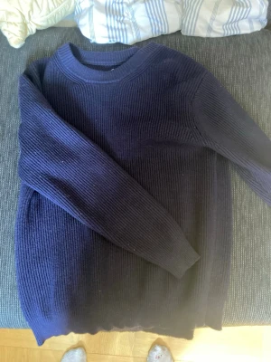 Maison margiela tröja blä - En stilren mörkblå ribbstickad tröja med rund hals och långa ärmar. Tröjan har en klassisk passform och är perfekt för lager-på-lager. Materialet ser ut att vara mjukt och värmande, 
