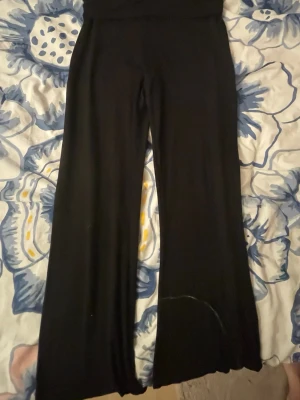 Svarta utsvängda leggings - Säljer ett par svarta leggings med utsvängda ben och hög midja. Materialet känns mjukt och stretchigt, perfekt för en chill och avslappnad stil. Passar till sneakers eller boots för en trendig look.