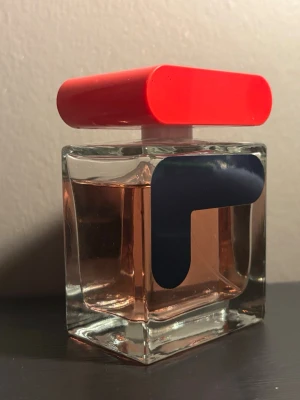 Fila parfym  - Härlig soft doft. Kan användas till vardags men även till fest. Unik parfymflaska i glas med en rektangulär form och en stor, klarröd kork. Flaskan har en ljusrosa vätska och ett stilrent, mörkblått grafiskt tryck på framsidan. Perfekt för dig som gillar trendiga och färgstarka detaljer på ditt sminkbord.