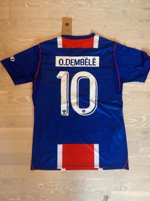 PSG 26/27 T-shirt  O. Dembélé #10 - Säljer en fet ny PSG T-shirt med dembele på ryggen.   Storlek är M och måtten finns på sista bilden.                         Den har aldrigs använts och är helt ny.                                  Priset kan diskuteras och skickar inom 24 Tim 💨☺️