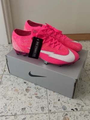 NIKE MERCURIAL VAPOR 13 ELITE FG MBAPPÉ ROSA - PINK BLAST/VIT/SVART - Säljer mina Mbappe skor som aldrig kommit till någon användning då de är för små. De har bara legat och samlat damm så tänker att det är dags att sälja. Storlek 43. Box och påse medföljer. Köptes för 2800