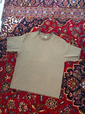 Beige kortärmad t-shirt - En enkel beige t-shirt med rund hals och korta ärmar. T-shirten har en rak passform och är tillverkad i mjuk bomull, perfekt för en avslappnad stil. Har en liten fläck som säkert går bort i tvätten.