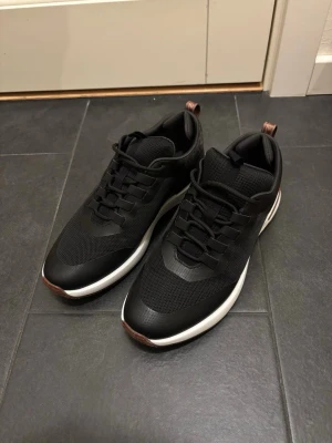 Svarta loro piana skor - Stilrena svarta sneakers med vit sula och bruna detaljer. Ovandelen är i mesh och syntetmaterial för bra andningsförmåga och komfort. Skorna har svarta snören och en modern, sportig look som passar till det mesta. Bra skick, ingen box endast skor!!!!!