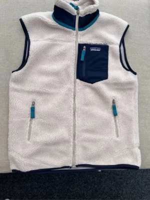 Patagonia Väst - Patagonia fleeceväst 🤍💙  Strl L men passar mer som M. Superfin teddyfleece med blå detaljer och flera fickor med dragkedja. Perfekt till höst, vår och svala sommarkvällar.  Bra skick! ✨  