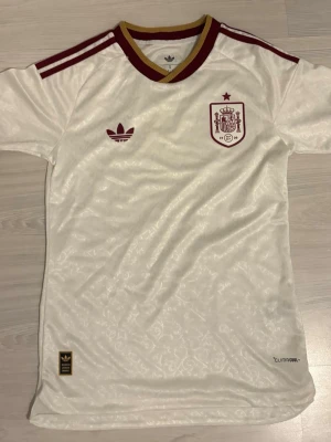 Vit Spanien fotbollströja Adidas - Spaniens VM tröja från 2026. Den är i bra skick och använts max 2 gånger. Den har storlek S men skulle säga att den passar XS. Perfekt för dig som vill bära tröjan i minne av deras fina vinst. Priset kan diskuteras 