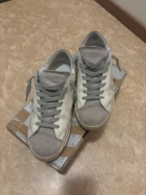 Vita skor from Golden Goose  - Vit/Gråa skor från Golden Goose. Snygga och fräscha skor inför sen sommar/höst. Inga trasiga tecken på skorna utan det som syns är smuts. Kartong och inplastning tillkommer. 