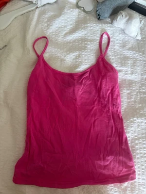 Rosa linnetopp med smala axelband - Säljer en enkel och snygg rosa linnetopp i storlek XS. Toppen har smala axelband och ärmlös design, perfekt för varma dagar. Materialet känns mjukt och lätt mot huden. Passar till jeans, kjol eller shorts för en avslappnad look.