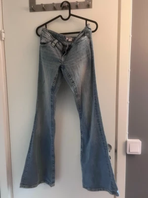 Ljusblå jeans, bootcut, low waist jeans  - Low waist blå jeans, lite sönder slitna längst ner på byxorna men är fortfarande i rätt så bra skick och även nån sorts svart  färg på jeansen som skulle kunna tas bort med tvättmedel