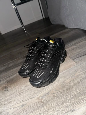 Nike Air Max Plus svarta sneakers - Svarta Nike Air Max Plus sneakers med vita detaljer och TN-logga på plösen. Skorna har en sportig design med mesh och syntetmaterial, samt synliga Air Max-enheter i sulan för extra komfort. Snygga kontrastsömmar och robust yttersula.